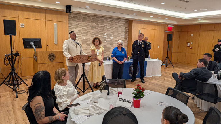 Guests and honorees look on as a speaker talks at the podium
