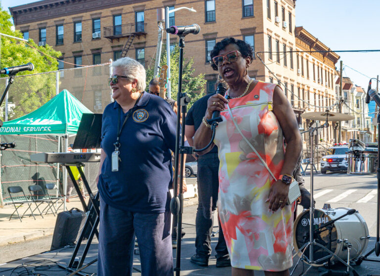 Person speaks into microphone at health fair outside VIP Community Services building in the Bronx
