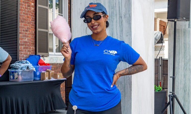 Women poses with cotton candy at community fair outside VIP Community Services building in the Bronx