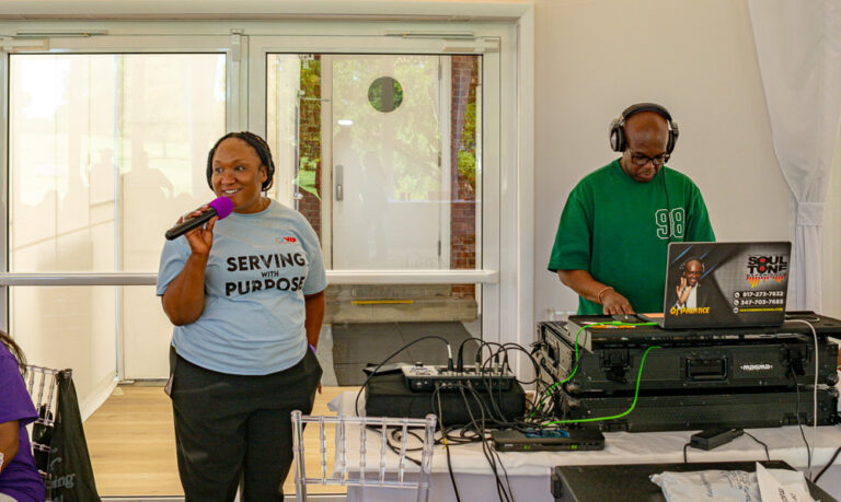 Staff speaks into microphone next to DJ for Staff Appreciation Day at VIP Community Services