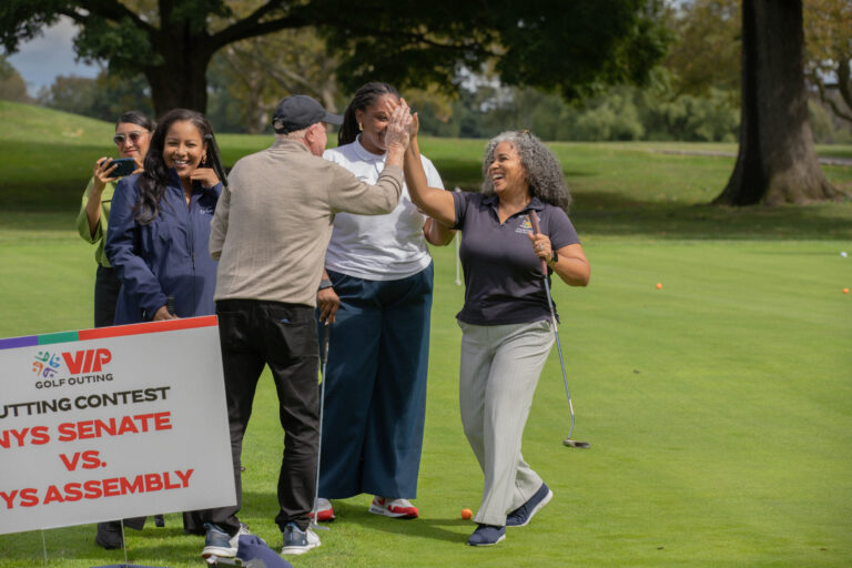 NYS Senate and NYS Assembly putting contest. Participants high five.