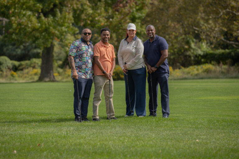 Attendees pose for photo on turf while playing golf at VIP's Inaugural Golf Outing 2026.